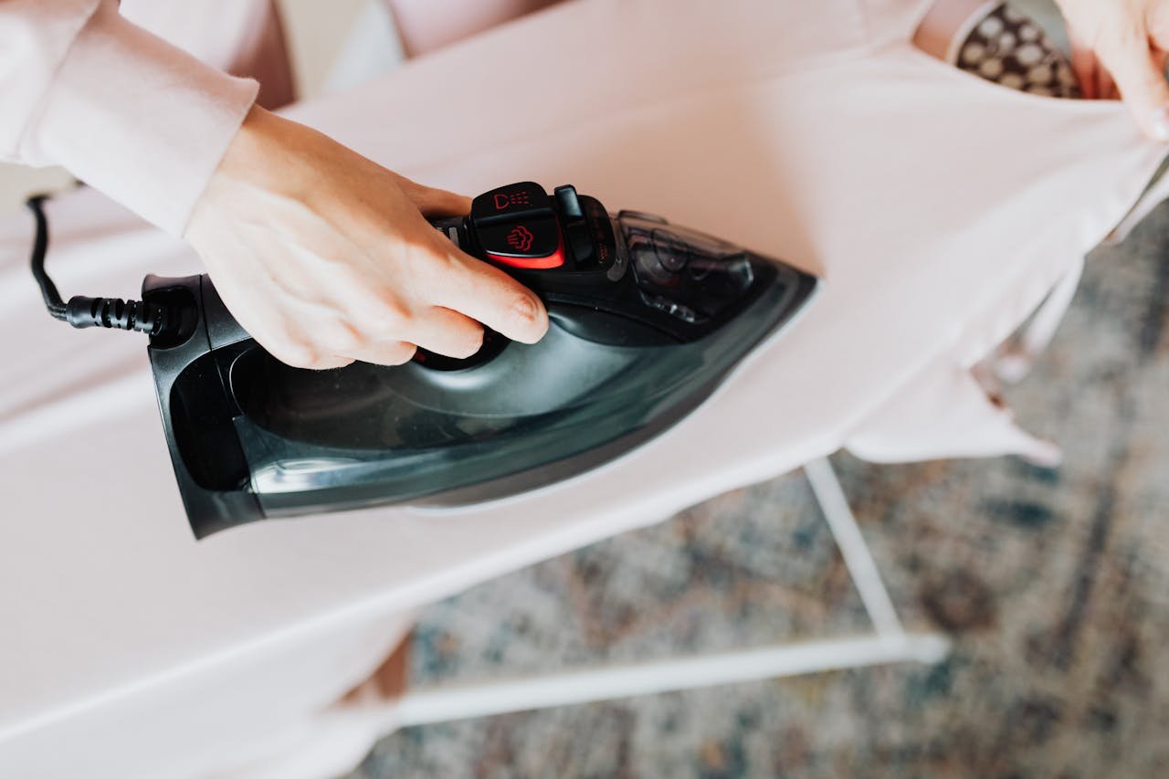 Overhead view of a person ironing clothes on a board at home, showcasing a domestic chore.
